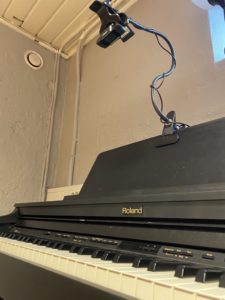 et kamera på stativ over pianotangentene